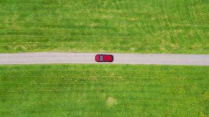 Obraz premium Aerial view looking down on a rural road in the Finland countryside with a car racing along it.