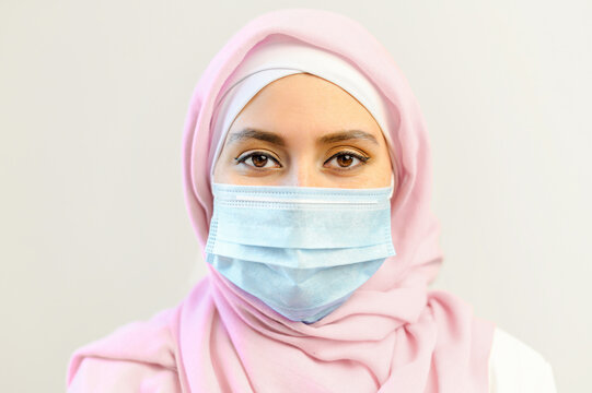 Pandemic lifestyle concepts. Close-up portrait of islamic woman wearing face mask and hijab during coronavirus epidemic, muslim businesswoman protects itself from viruses, isolated on white