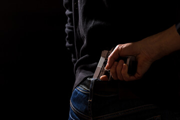 The man hides the gun behind his back. Prepare weapons, Permit to carry weapons. Free sale of...