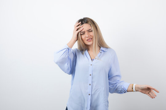 Image of blonde beautiful woman holding her head on white background