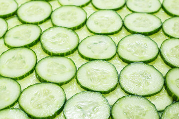 Fresh green slices of cucumber as background.
