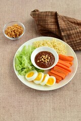 Gado-gado, traditional Indonesian salad with peanut sauce on brown background