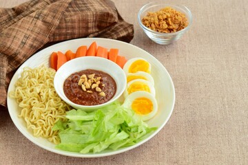 Gado-gado, traditional Indonesian salad with peanut sauce on brown background