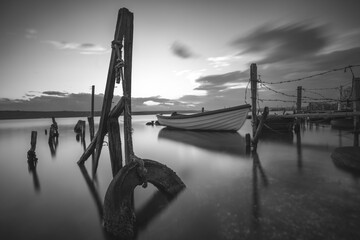 Small dock and fishing boat at fishing village, black and white long exposure