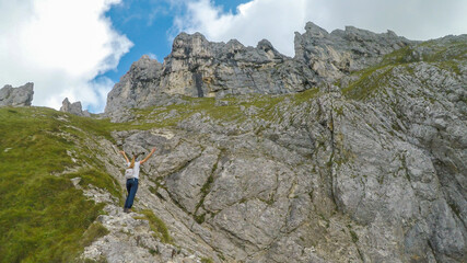 A backpacker woman hiking through Austrian Alps to the top of Hochkogel. She is walking across a...