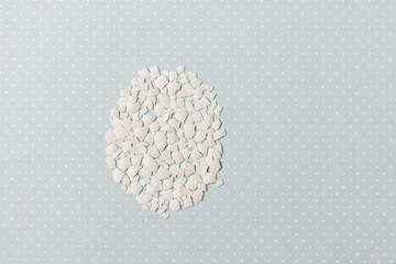 Pieces of white shell chicken egg, folded in the shape of an egg on a blue background, easter pattern