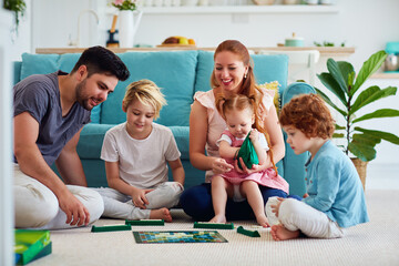 cheerful family having fun, spending time together by playing board games at home - 418357134