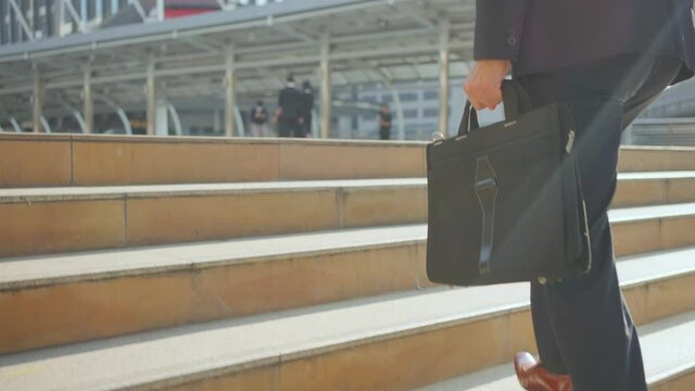 Close-up shot of Asian businessman walking up on stair, going to work.