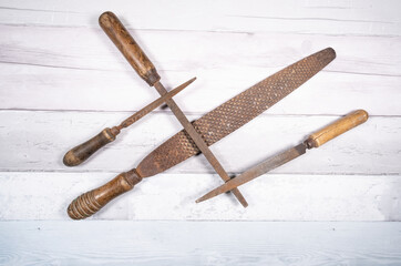 Sets of different wood rasps of different sizes in the middle of an old wooden floor background....