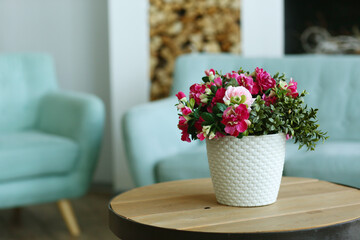modern bedroom closeup fragment with flowers in vase, sofa and pillows on background