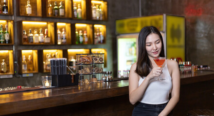 Young Asian woman with a sad face drinking cocktails in front of a vintage bar, Relaxing activities after work or hangouts, Place of entertainment for young adolescents or night club party.