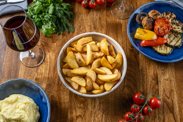 Potato wedges fries chips country style served with cherry tomatoes. Enjoying tasty vegan food with friends in restaurant. Selective focus