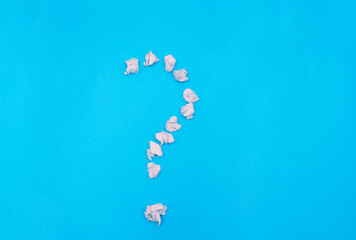A question mark on a blue background. The question mark is made of crumpled paper.