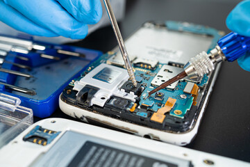 Technician repairing inside of mobile phone by soldering iron. Integrated Circuit. the concept of data, hardware, technology.