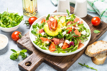 Green salad with avocado, salad leaves, jamon serrano and tomatoes. Healthy diet lunch.