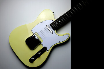 Obraz premium Yellow colored vintage electric guitar on a white and black background - close up