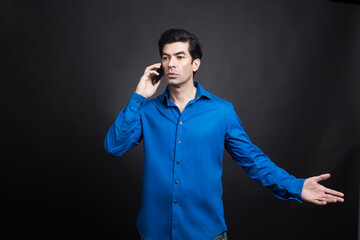 uomo moro in camicia blu uomo moro in camicia blu parla al cellulare con espressione seria, isolato...