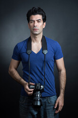 fotografo moro in maglietta blu e fotocamera al collo è in attesa  , isolato su sfondo nero