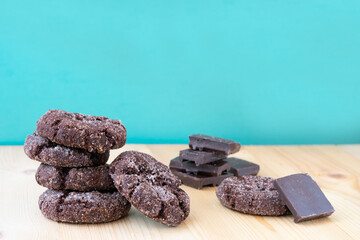Pile of chocolate cookies on wooden table. Freshly home made baked choco sugary biscuits on blue background