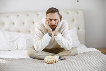 Man hold remote control. Guya in living room at home, with copy space.