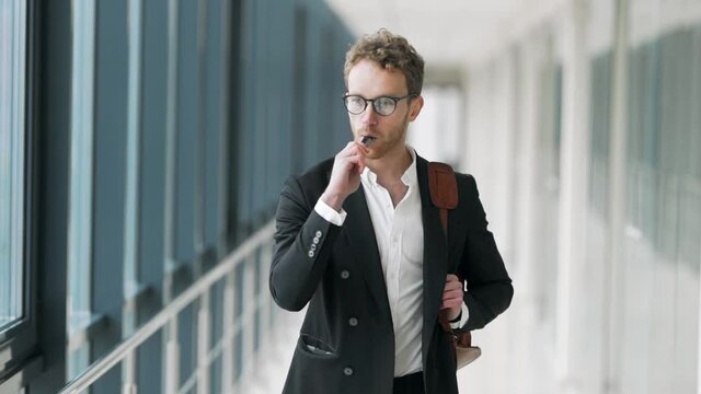 Cute stylish man smokes an electronic cigarette walking down the hall