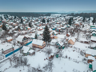 Traditional Russian dacha village near the lake and forest in winter, aerial view