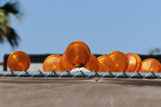 Traffic barrier orange lights stored behind fence at construction site