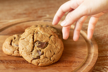 Delicious Homemade Chocolate Chip Cookies. Chocolate chip cookies on plate on wooden background. Warm, golden brown, chocolate chip cookies cooling on baking paper. Natural handmade organic cookies.