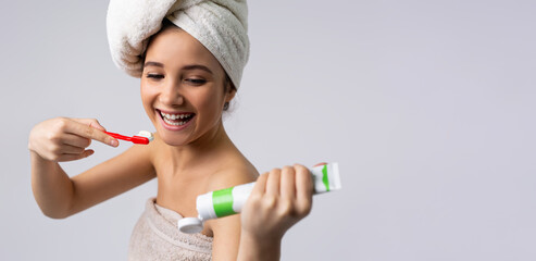 Banner,long format. A girl with a towel on her head smiles and brushes her teeth. Oral cavity care. Side advertising space.