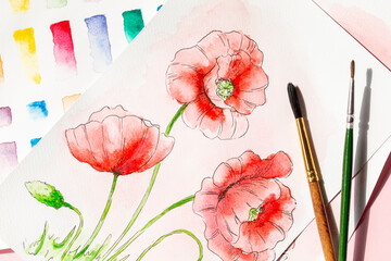 Watercolor painting with poppy flowers and artist brushes, top view