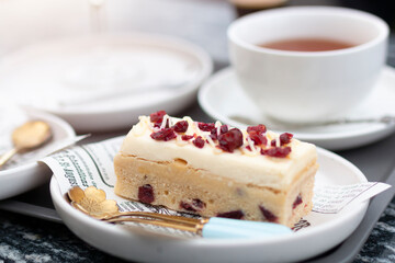 Cheesecake slice with dried raspberries on white plate. Slice of cheesecake. Raspberry cheesecake. Homemade cheesecake with dried berries for dessert with cup of tea.