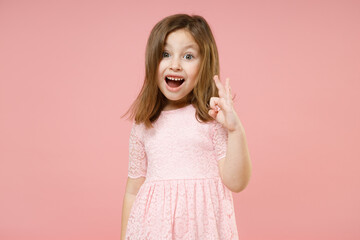 Little kid girl 5-6 years old wears rosy dress shows okay ok zero fingers gesture isolated on pastel pink background child studio portrait. Mother's Day love family people childhood lifestyle concept.