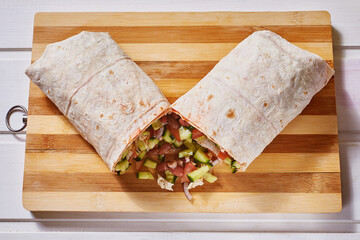 Vegan doner roll with beans in pink pita bread on a white wooden background.