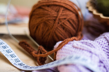 Cozy homely atmosphere. Female hobby knitting. Yarn in warm colors. Pink, peach, beige, white and green. The beginning of the process of knitting a women's sweater.