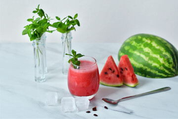 Fresh watermelon juice with mint and ice in the glass on white table.Sweet summer dessert, smoothie,cocktail healthy food concept, close up.Summertime. Copy spase. Selective focus