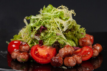 Small grilled sausages with green lettuce and tomatoes