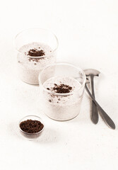 Italian dessert panna cotta with chocolate chip cookie crumbs in a glass on a white background
