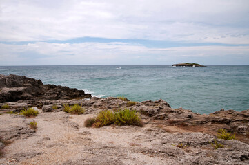 Rocky shoreline of the Calanca cove with its small islet, Marina di Camerota, Italy.