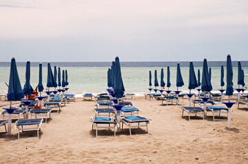 Typical Italian lido on a sandy beach with umbrellas and sunbeds closed in the evening in front of...
