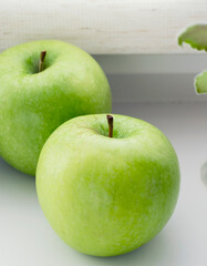 Ripe green apples on a white window. Juicy fruits on a white background.