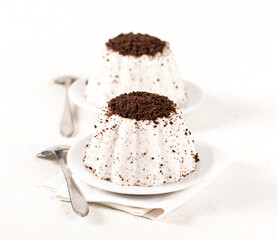 Vanilla creamy pudding with chocolate chip cookie crumbs on a plate on a white background