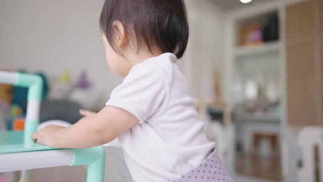 Asian baby girl playing around inside condo apartment bedroom, kids playground at home, child toys online ordering, happy positive energy from young age, children emotion sensitivity study concept