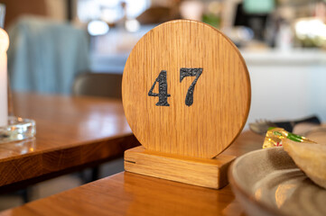 A wooden sign with number 47 marking the visitors queue number waiting for food as part of new normal at restaurants after Covid-19 - obrazy, fototapety, plakaty
