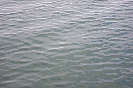 Repeated pattern of waves and ripples caused by a breeze on a natural water surface.  