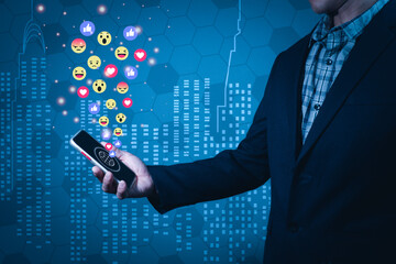 A man wearing a suit holds a mobile phone forwarded in a manner that reads a message on the screen. There are emojis emitting from the screen. Abstract background