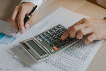 Close up hand of stress young asian businessman,male is pressing a calculator to calculate tax income and expenses, bills, credit card for payment or payday at home, office.Financial, finance concept.