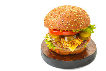 Classic burger with beef, cheese vegetables in sauce with mustard on a wooden round stand on a white background isolate.