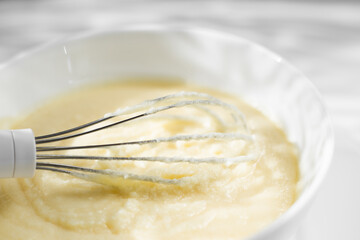 Cream whipped with mixer in a plate on a white background. Close-up cake cream. Light rays fall on the table