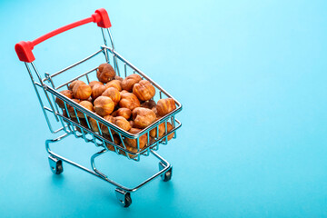 Food cart filled with peeled hazelnuts on a blue background. Copy space.