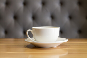 White cup and saucer on wooden table in living room interior